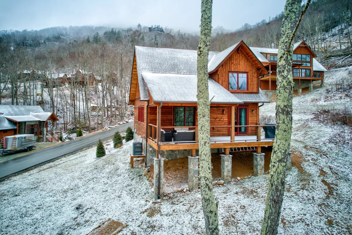 This image features a charming wooden cabin nestled among snowy trees, with the ground blanketed in fresh snow. The cozy atmosphere is enhanced by the natural setting, suggesting a welcoming retreat where families can gather, play, and explore the outdoors together.